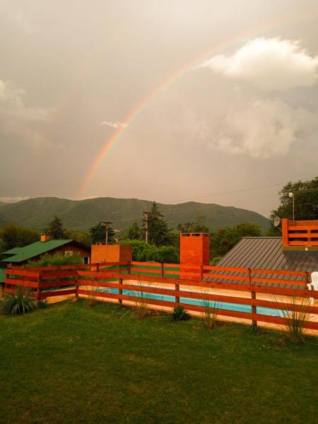 un arco iris está en el cielo sobre una valla en Cabañas Puentes Amarillos, en Santa Rosa de Calamuchita