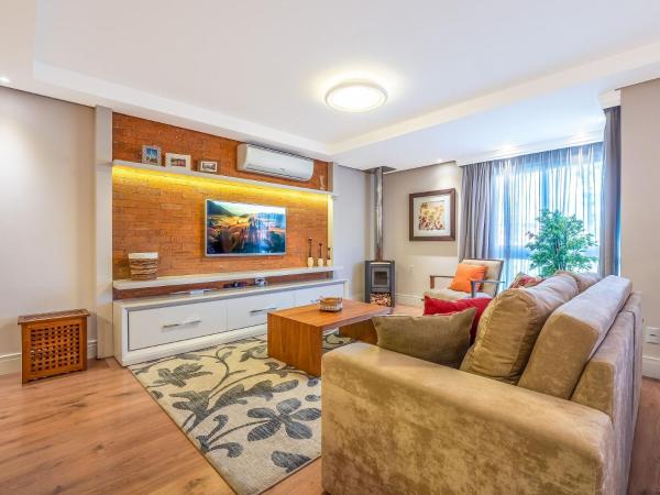 sala de estar con sofá y TV en Vivendas da Montanha 102 - Apto em Gramado junto ao Hotel Colline de France, en Gramado