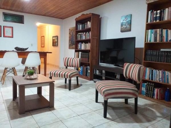 sala de estar con TV, sillas y mesa en Iguazu House en Puerto Iguazú