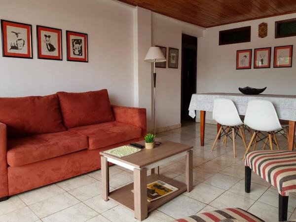 sala de estar con sofá rojo y mesa en Iguazu House en Puerto Iguazú