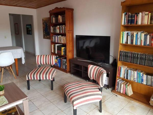 sala de estar con 2 sillas y Tv LED en Iguazu House en Puerto Iguazú