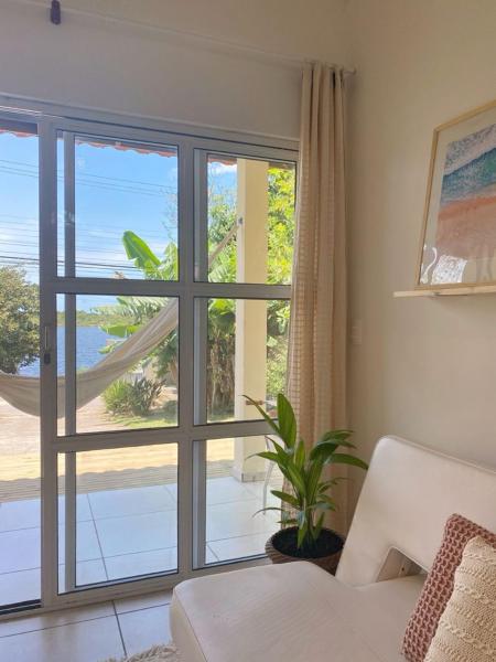 a living room with a large window with a view of the ocean at Loft à Beira da Lagoa com Vista Deslumbrante! O melhor de Floripa - Novo Campeche in Florianópolis