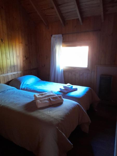 2 camas en una habitación de madera con toallas. en Departamentos Sonne Depto Planta Alta en San Martín de los Andes