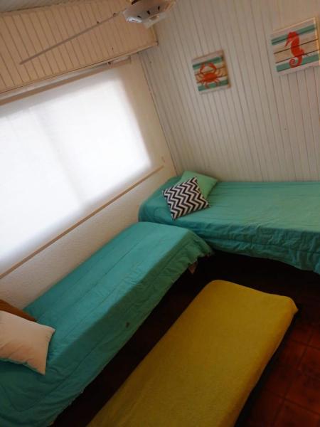 2 camas en una habitación pequeña con ventana a Encantador departament frente al mar 4 Con en Villa Gesell