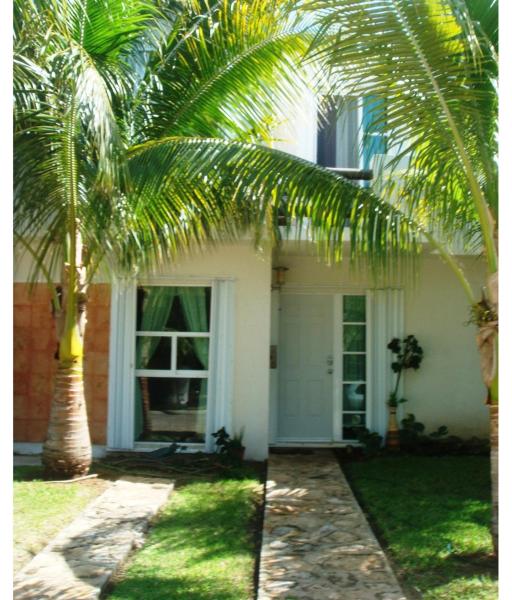 una palmera frente a una casa blanca en Acogedora casa en playa del Sol, en Playa del Carmen