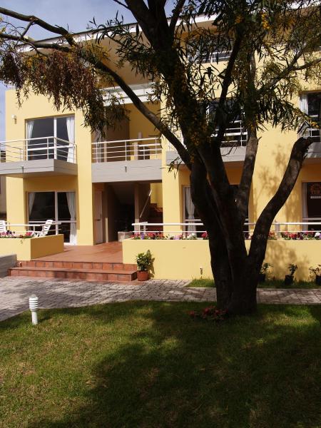 un edificio amarillo con un árbol en frente en Las Terrazas Departamentos Turisticos de Villa Gesell