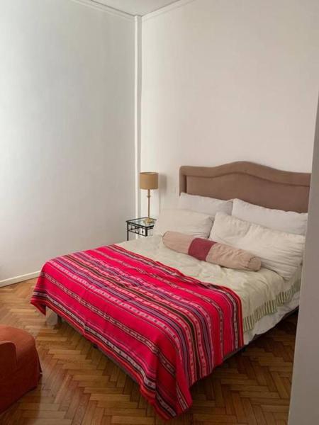 Un dormitorio con una cama con una manta roja. en Corazón de Recoleta en Buenos Aires