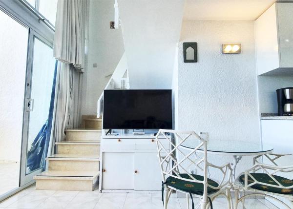 sala de estar con mesa y TV en Skol 701. One Bedroom Duplex with Exceptional Sea Views., en Marbella
