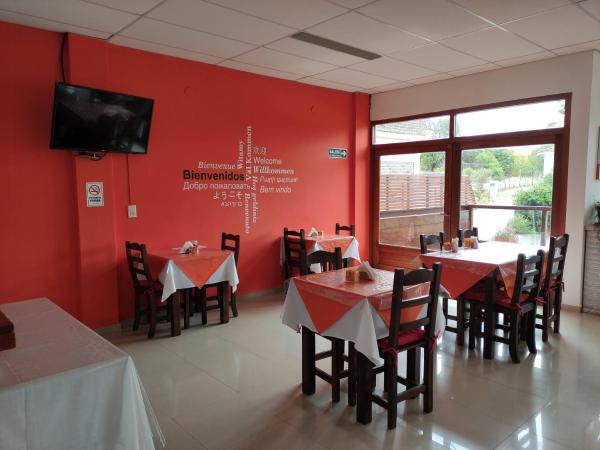 un comedor con paredes rojas y mesas y sillas en la Hostería Ymaz de Villa Gesell
