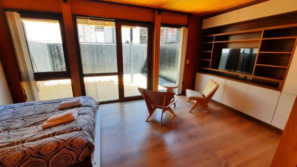 sala de estar con cama, sillas y ventanas en Hermoso monoambiente con jardin, modernoso y cálido a media cuadra de la calle principal (V406) en San Martín de los Andes
