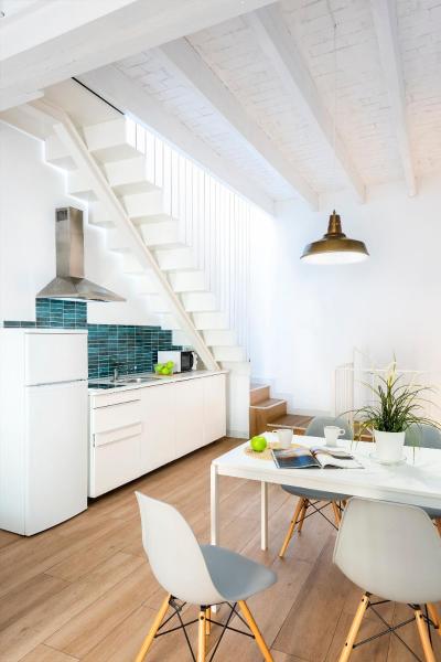 cocina con armarios blancos, mesa y sillas en HSH Suites Santa Catalina, en Sevilla