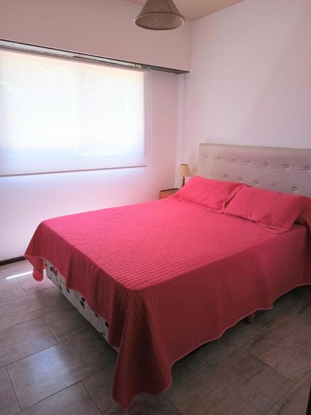1 dormitorio con cama roja y ventana a Edificio Familiar Mar Veo en Villa Gesell