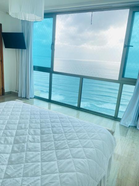 1 dormitorio con 1 cama blanca grande y ventana grande en Vista al mar Habitación Privada Coral en Malecon Santo Domingo 1-829-343-1001, en Santo Domingo