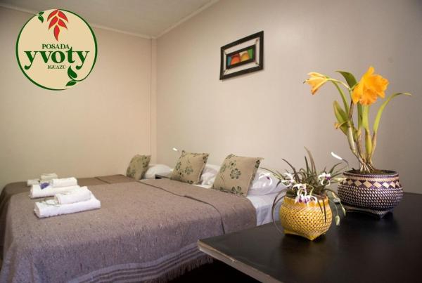 1 dormitorio con 1 cama y 1 mesa con flores en Posada Yvoty en Puerto Iguazú