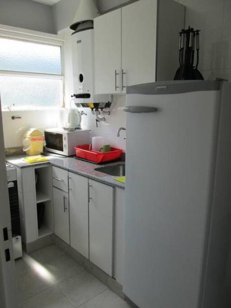cocina con armarios blancos y refrigerador blanca en Depto para 4 personas Centro Salta capital en Salta
