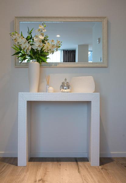 a console table with a mirror and a vase with flowers on it at Amarras Center in Santa Fe