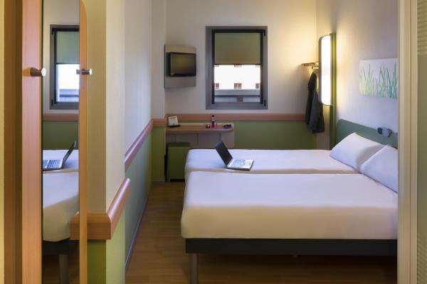 una habitación de hotel con 2 camas y un ordenador portátil.  en Ibis Budget Sevilla Aeropuerto, en Sevilla