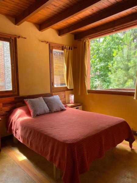 1 dormitorio con 1 cama roja y 2 ventanas en Cabañas Los Castores en el Balneario Mar Azul