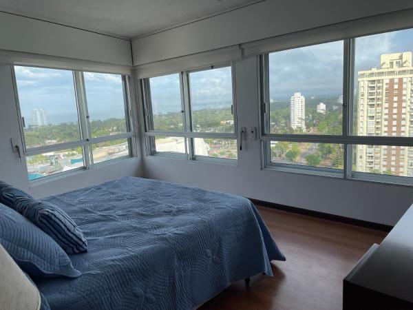 1 dormitorio con ventanas y 1 cama con sábanas azules en Sunset, en Punta del Este