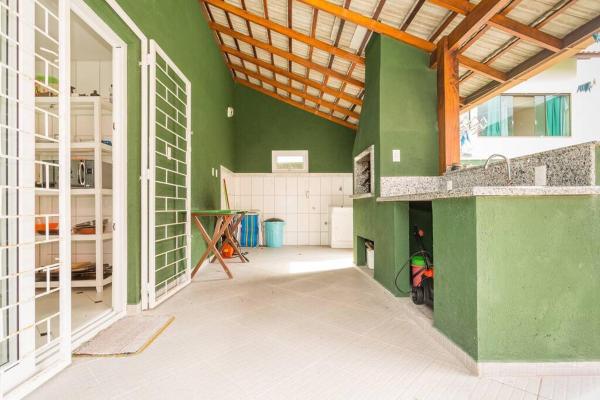 a room with green walls and a kitchen with a counter at Campeche Beach House in Florianópolis