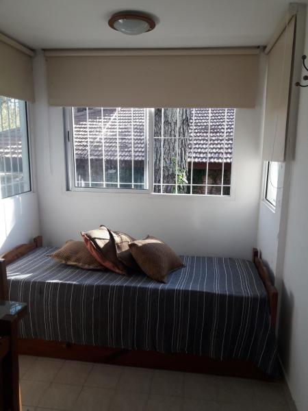 1 cama con 2 almohadas en una habitación con 2 ventanas en valle encantado en Pinamar