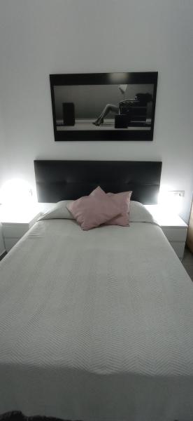 Cama blanca con almohada rosa y espejo en Loft cerca del centro de Málaga, en Málaga