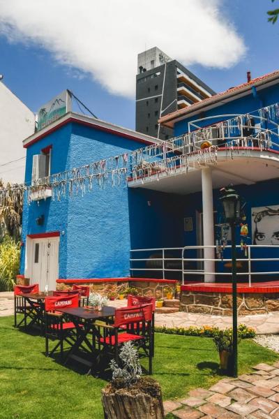 un edificio azul con sillas rojas y una mesa en Blau Hostel, en Villa Carlos Paz