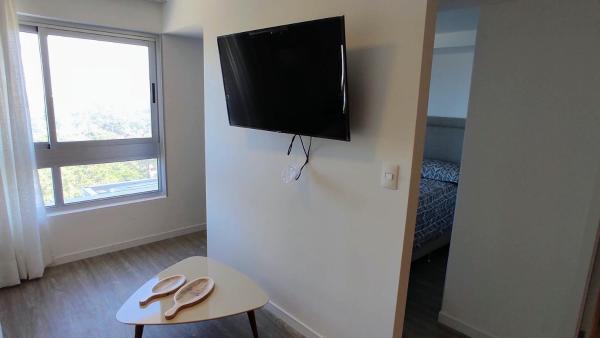 una habitación con TV en la pared y dos zapatos en una mesa en Ocean Drive Country, en Punta del Este