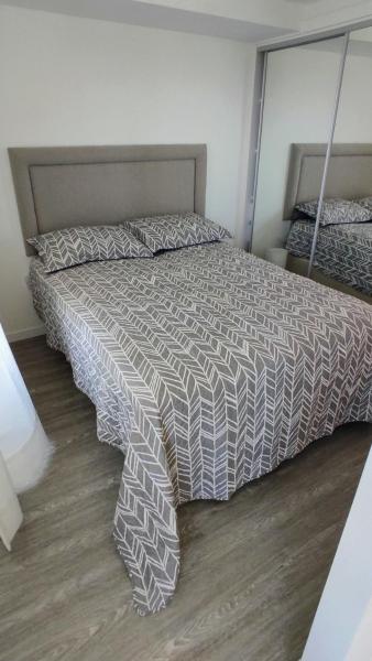1 dormitorio con 1 cama con edredón gris y blanco en Ocean Drive Country, en Punta del Este