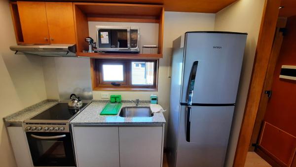una pequeña cocina con refrigerador y fregadero en Hermoso monoambiente en el centro de SMA, muy cálido y modernoso V407 en San Martín de los Andes