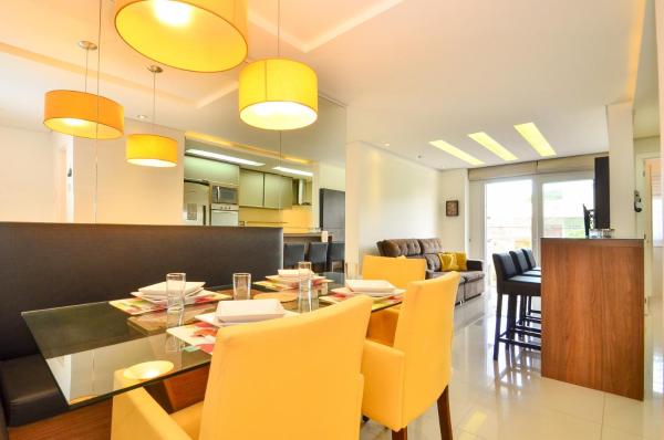 a kitchen and dining room with a dining table and yellow chairs at Jurerê para 6 hóspedes a 2 quadras da praia N1705 in Florianópolis