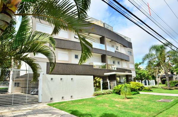 a building with a palm tree in front of it at Jurerê para 6 hóspedes a 2 quadras da praia N1705 in Florianópolis