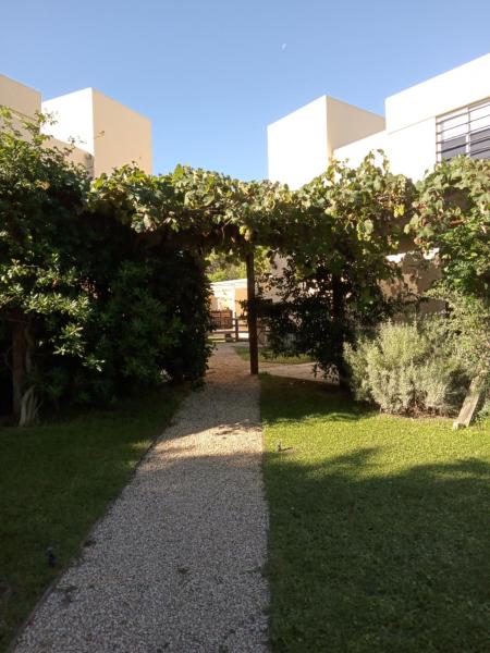 un jardín con pérgola frente a un edificio en DÚPLEX EN EL SUR en Villa Gesell