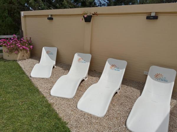 cuatro sillas blancas de jardín sentadas en un patio en DÚPLEX EN EL SUR en Villa Gesell