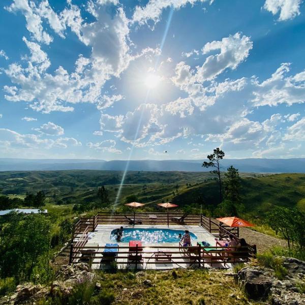 una piscina en la cima de una colina con el sol en el cielo en Cabañas PAIGÜEN, en Villa Yacanto