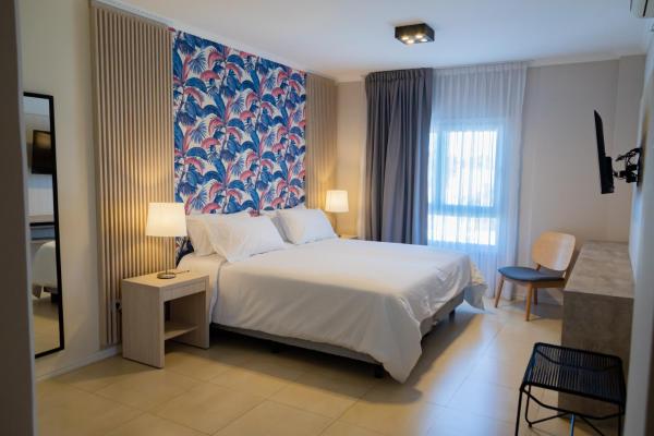 Un dormitorio con una cama blanca y una pared floral azul en Garden Suites Pinamar en Pinamar
