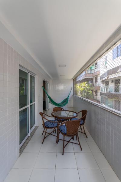 balcón con mesa, sillas y hamaca en Pé Na Areia Recreio, en Río de Janeiro