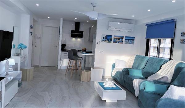 sala de estar con sofá azul y cocina en My Sweet Santorini, en Benidorm