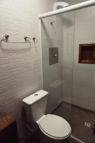 a bathroom with a toilet and a glass shower at Graffi Beach Hostel in Florianópolis