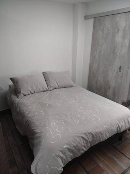 1 cama en un dormitorio con colcha blanca en Estudio RUFINA IV en el corazón de Mendoza, en Mendoza
