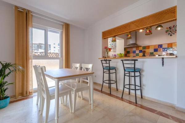 cocina y comedor con mesa y taburetes en Luminoso apartamento de dos habitaciones con terraza y parking en el centro, en Málaga