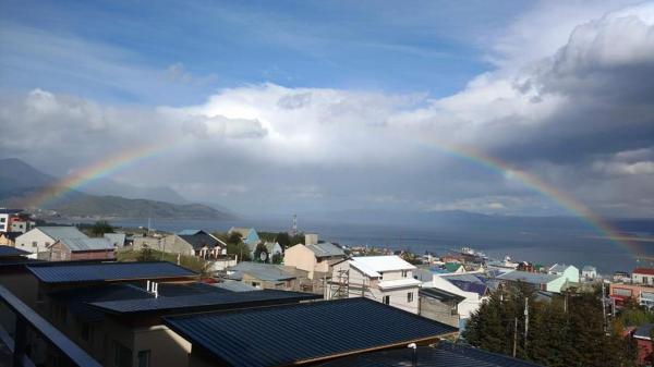 un arco iris en el cielo sobre una ciudad con edificios en el Apart del sur de Ushuaia