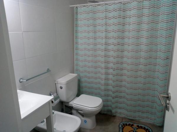 y baño con aseo y cortina de ducha. en Departamento Ezeiza- ciudad de Tandil en Tandil