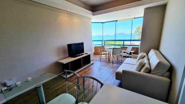 a living room with a couch and a television at Costa Blanca Standard - Beira Mar in Florianópolis