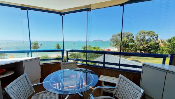 a room with a table and chairs and a view of the ocean at Costa Blanca Standard - Beira Mar in Florianópolis