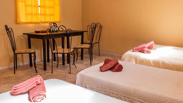 Habitación con 2 camas, mesa y sillas en Residencial Los Pinos en Puerto Iguazú