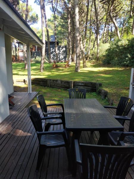 una mesa de madera y sillas en una terraza en Pinamar Norte Casa Aquiles 8 pax en Pinamar