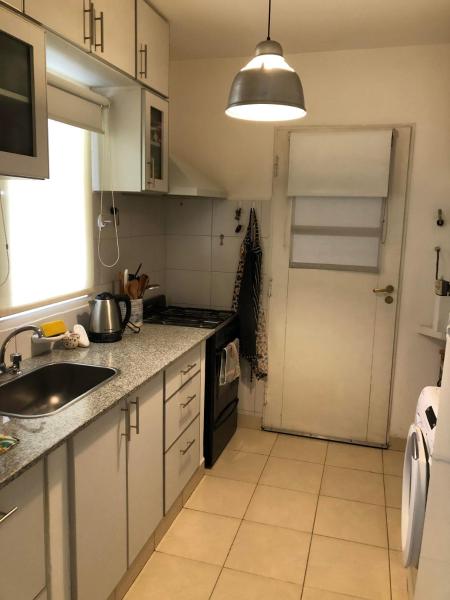 cocina con armarios blancos, fregadero y puerta en Cómoda habitación privada en casa compartida en Esquel