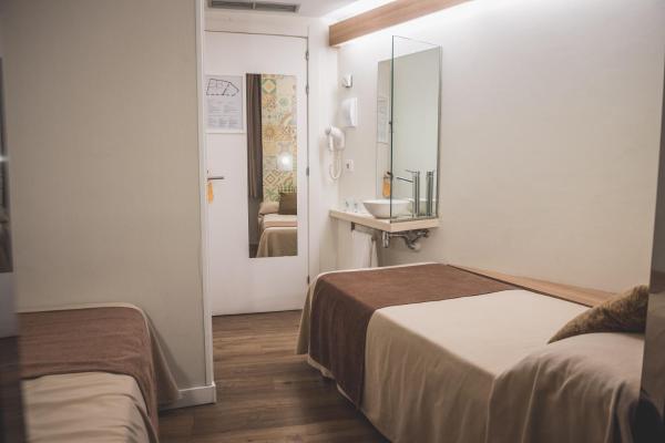Habitación pequeña con 2 camas y lavamanos en Hostal Marenostrum, en Barcelona