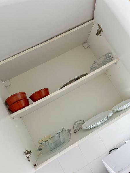 a white kitchen with two shelves with bowls and a sink at Alquiler Temporario Santa Fe in Santa Fe